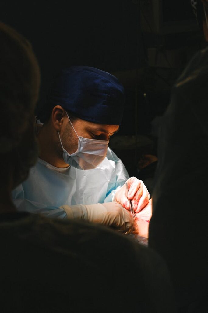 Surgeon focused during complex surgery with full surgical attire and equipment.